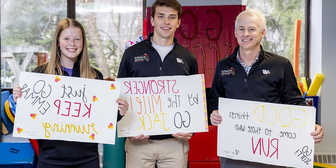 Three runners holding signs